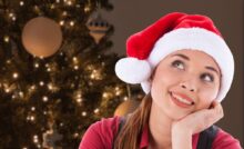 ragazza con cappello di natale e albero alle spalle